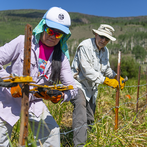 Two volunteers fix a fence in Fish Lake National Forest