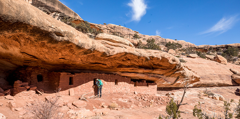 A hiker peers into an archaeological site in Bears Ears