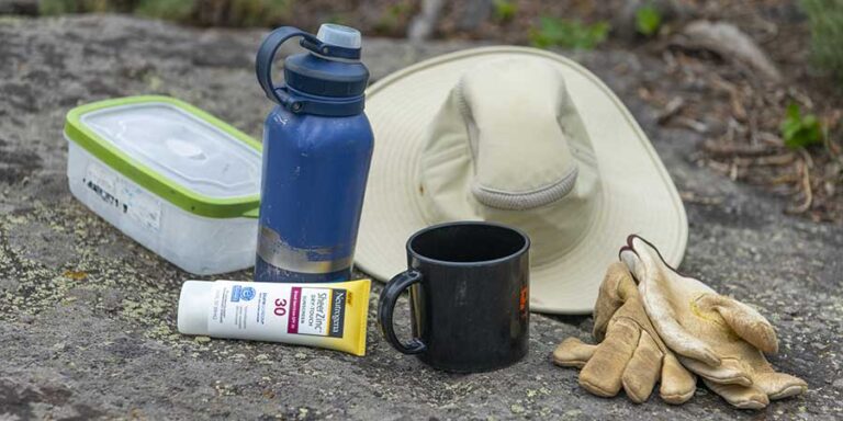 A large brimmed hat, a water bottle, tupper ware, a coffee cup, work gloves, and tube of sunscreen.