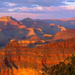 Sunset turns the cliffs of Grand Canyon National Park golden, orange, red, purple, and pink.