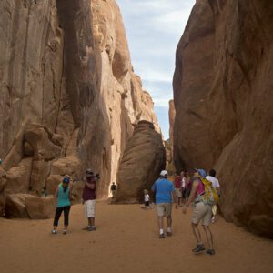 Hikers marvel at the steep sandstone walls in a canyon in Arches National Park