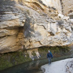A male hiker walks on sand in a deep canyon along the Boulder Mail Trail