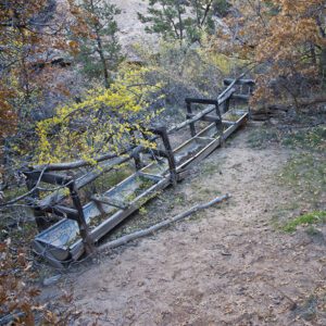 A wooden fence surrounds a long metal trough that holds spring water