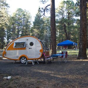 A campsite at the North Rim Campground with a tear-drop trailer, blue easy-up, folding chair, and table