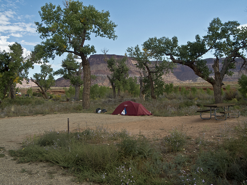 A red tent at a campsite with cliffs in the far distance