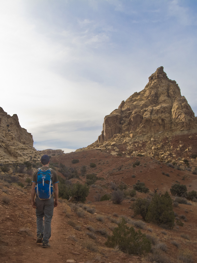 A hiker walks on the red slopes between Ding and Dang canyons