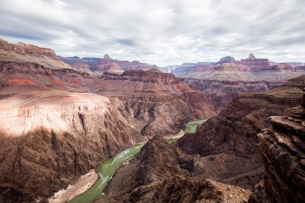 Emerald green Colorado River at the bottom of grand canyon cliffs