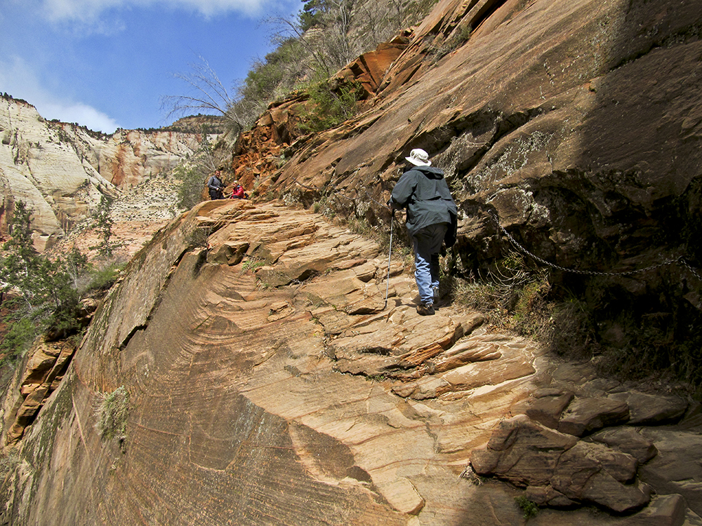 A male hiker climbs natural sandstone steps formed of ledges of rock