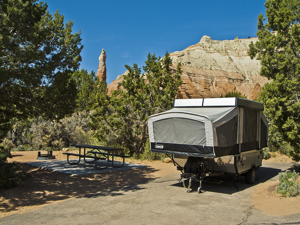 A pop-up camper and picnic table in front of red and white cliffs