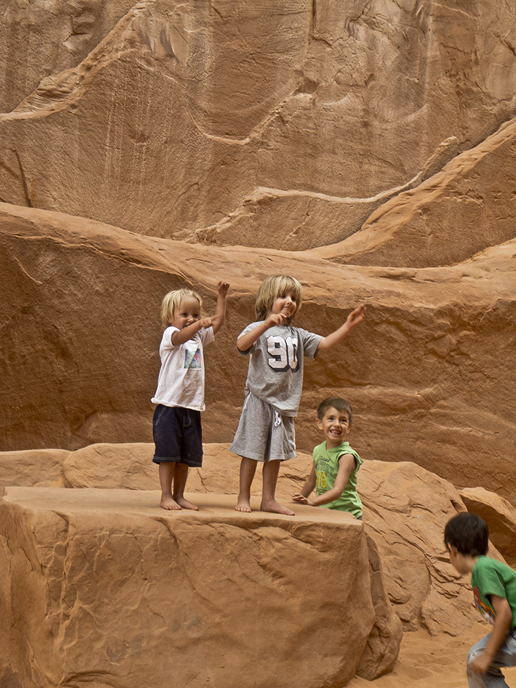 Kids play on a sandstone rock.