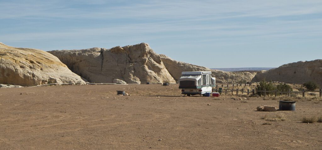 A pop up camper in a the dirt camping area of Temple Mountain Campground