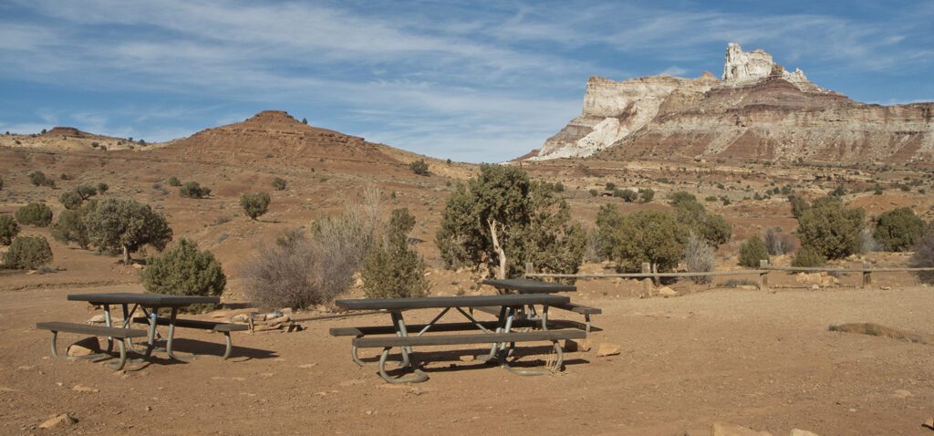 A picnic table in a big flat gravel area with hills in the background