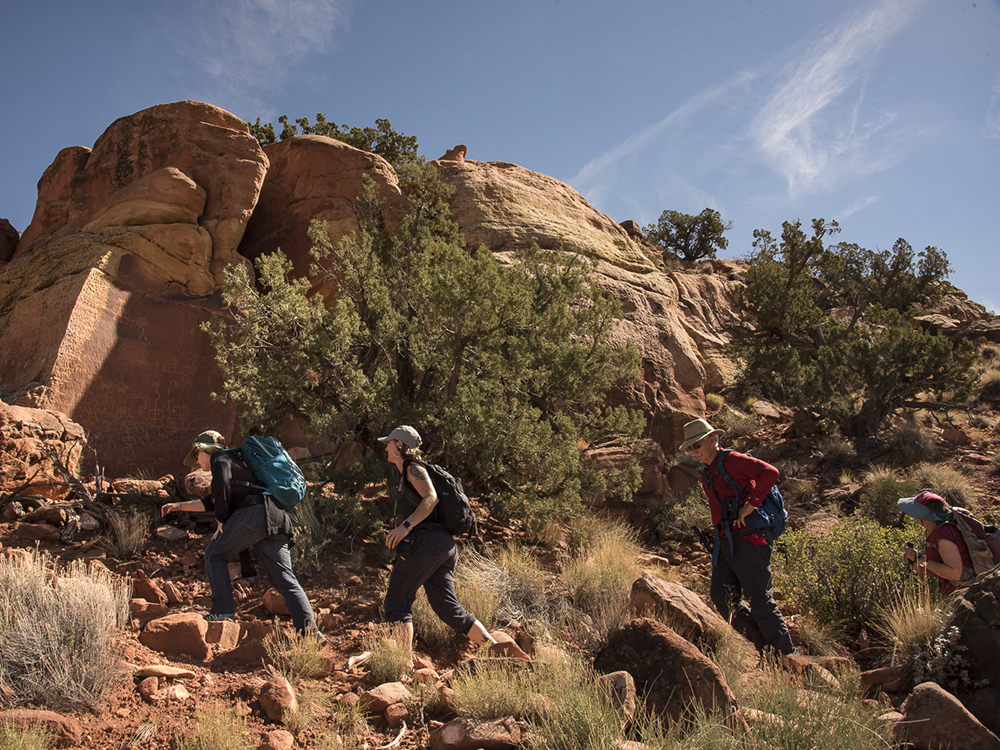 Trust donors hike near sandstone boulders.