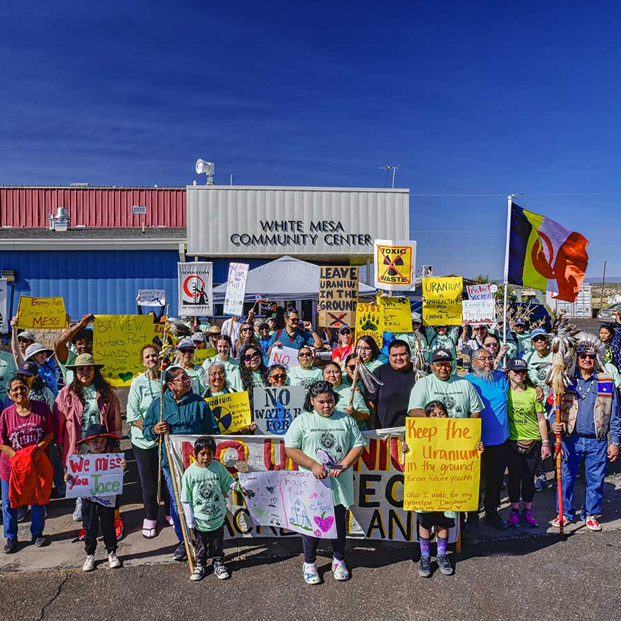Members from the White Mesa community stand in front of their community center with protest signs.