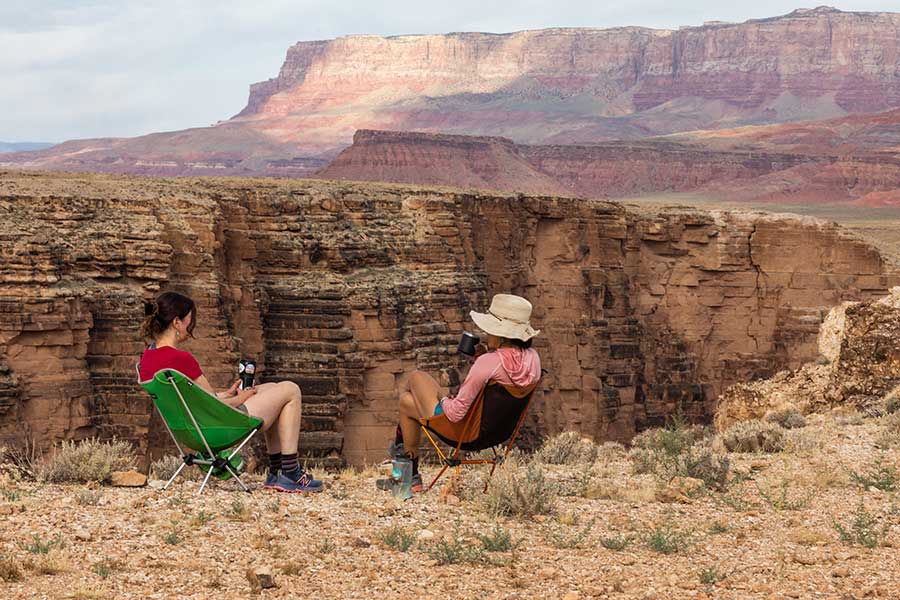 Two women in camping chairs sitting at the edge of marble canyon in Baaj Nwaavjo I'tah Kukveni National Monument