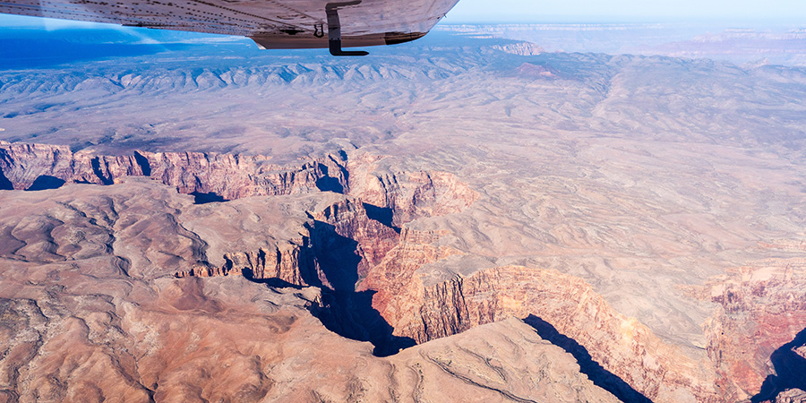 An aerial view of the Little Colorado River with the silver tip of the wing of the plane visible