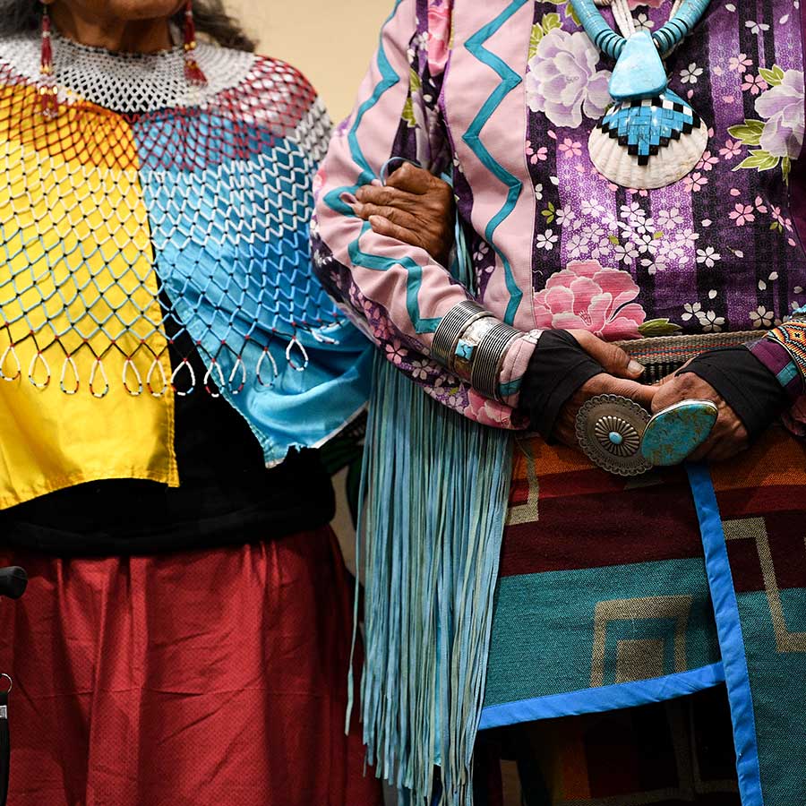 Two people link arms in colorful traditional Havasupai regalia at an intertribal gathering
