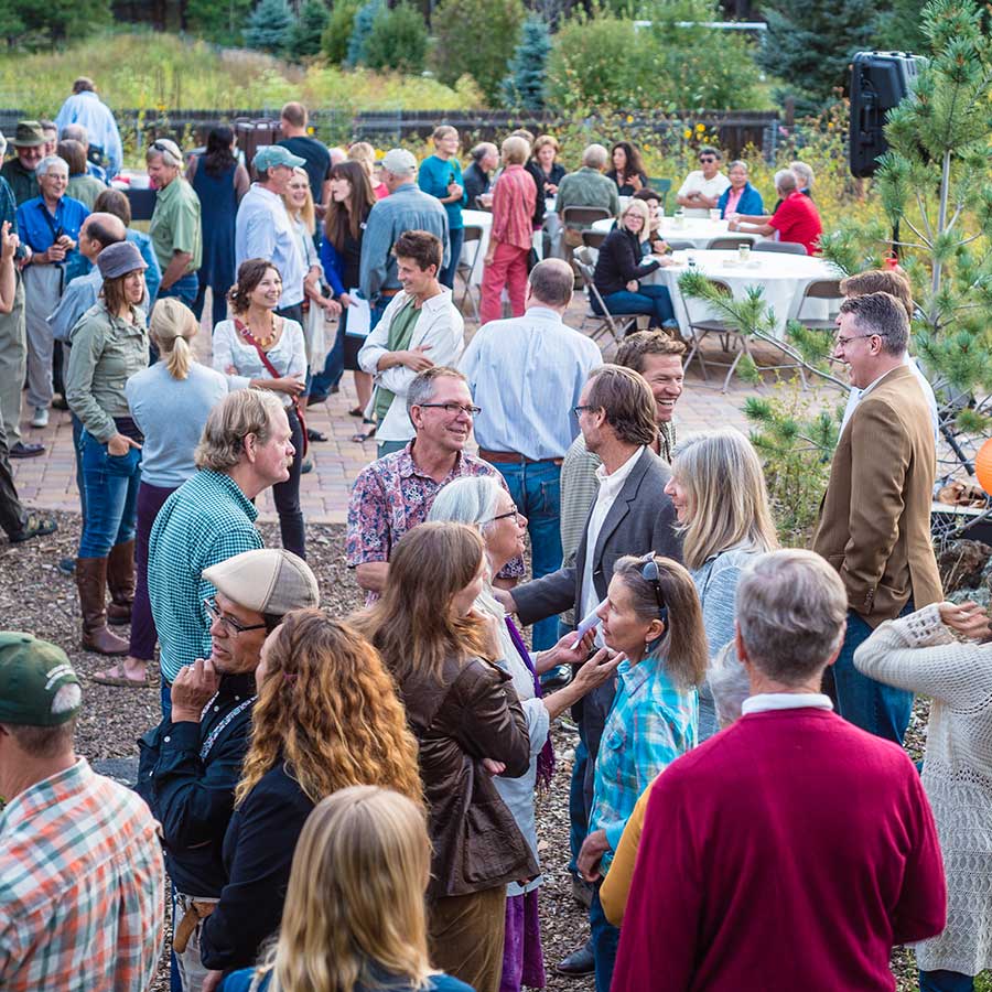 People in brightly colored clothing mingle on a patio during a Grand Canyon Trust membership party