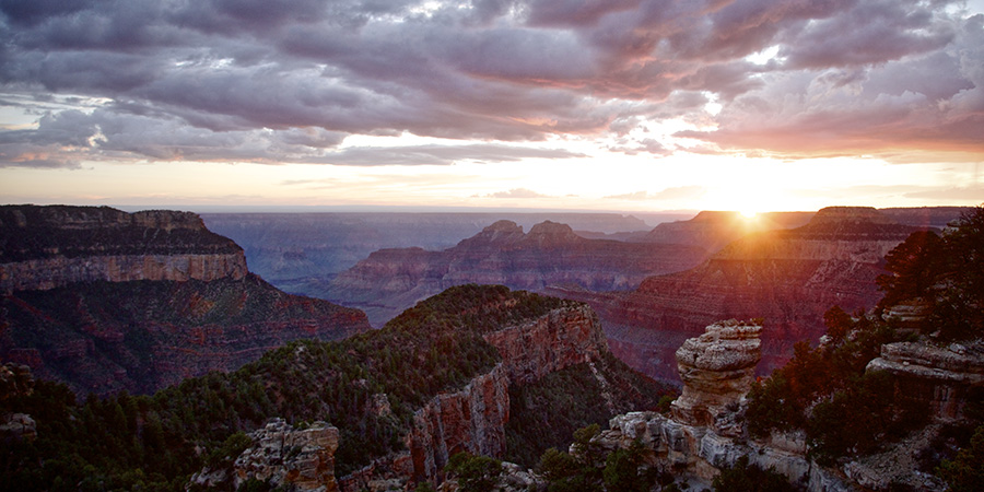 Sunstar at the edge of the Grand Canyon with dramatic clouds