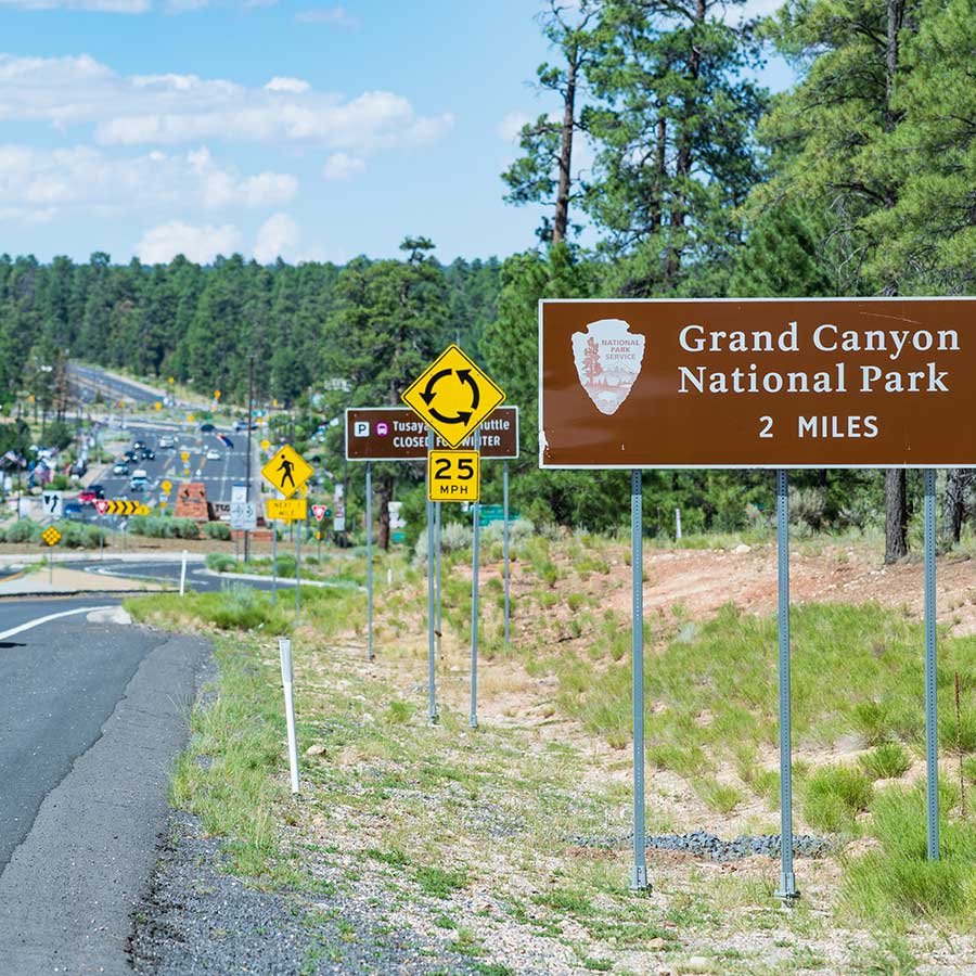 A brown road sign outside Tusayan indicating that Grand Canyon National Park is two miles ahead