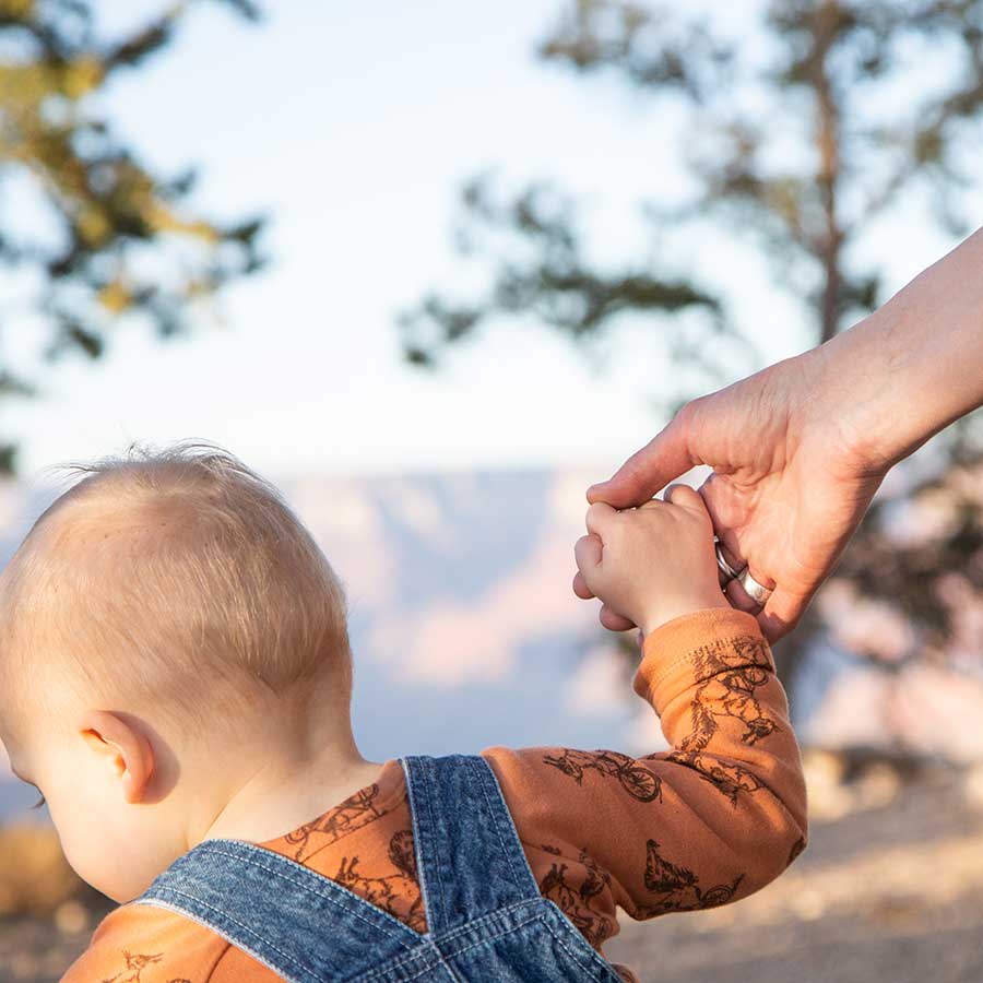 A baby holds his mom's hand at the Grand Canyon