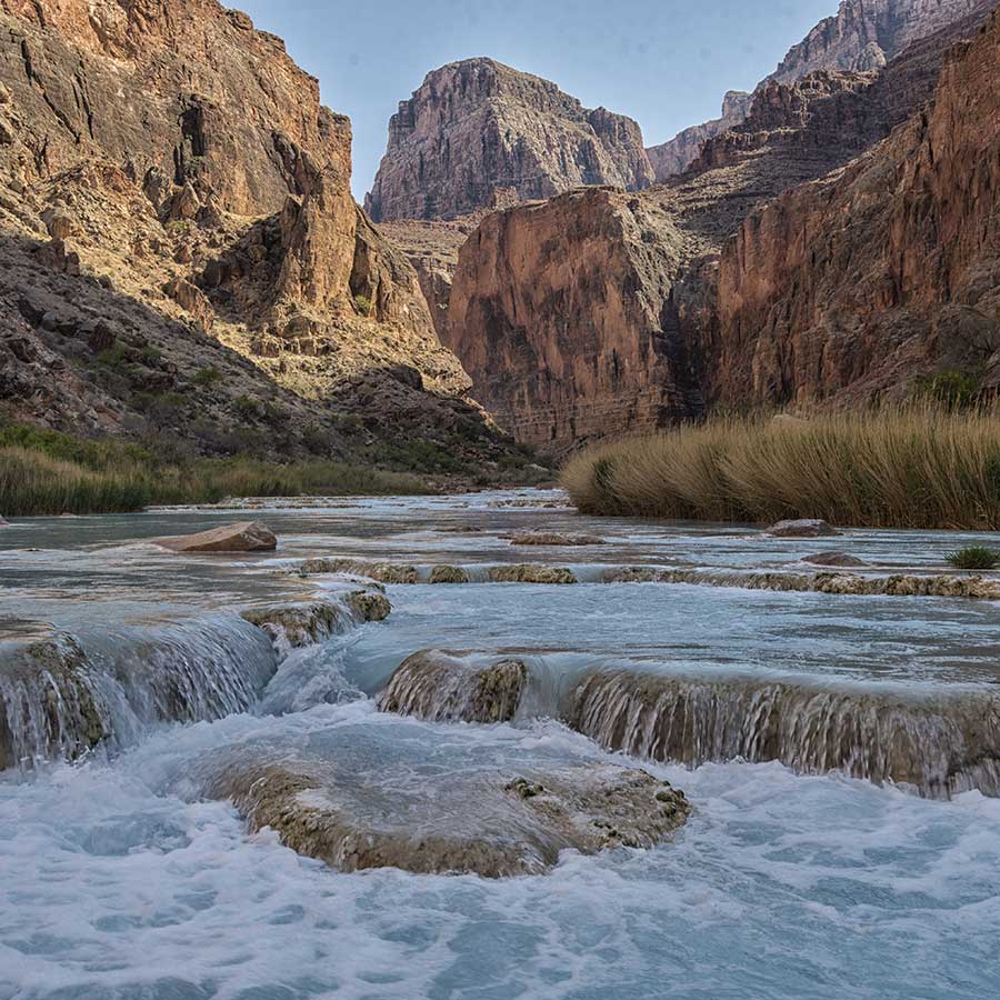 Milky turquoise falls in the Little Colorado River with cliffs in the background