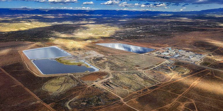 Aerial view of an Energy Fuels industrial site with multiple large rectangular water ponds, buildings, and dirt roads in a dry, sparsely vegetated landscape.