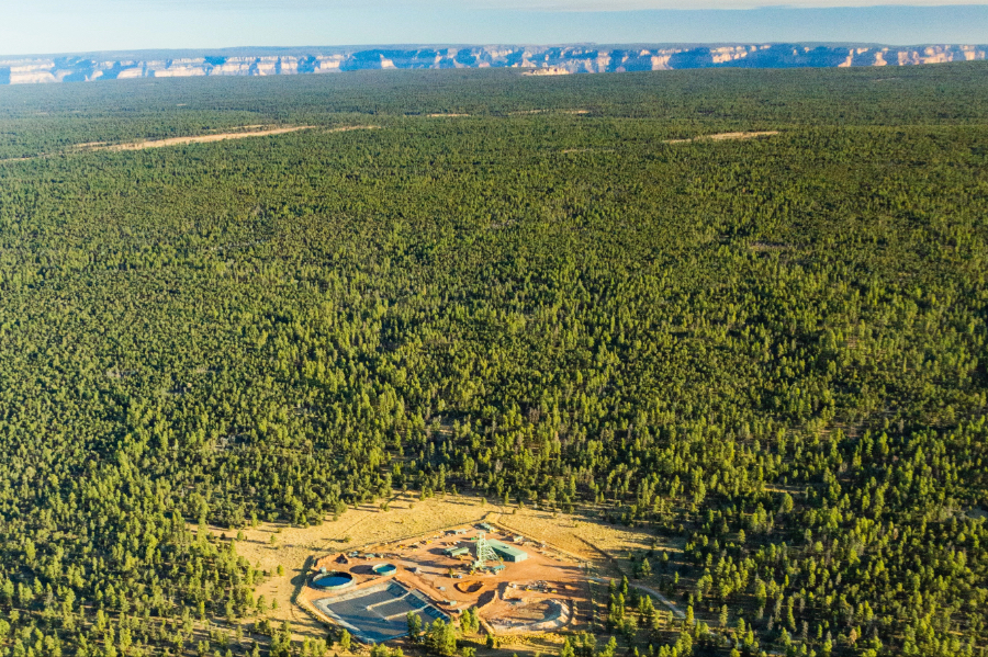 Aerial view of the Pinyon Plain uranium mine site surrounded by a dense forest, with Grand Canyon rim visible in the distance.
